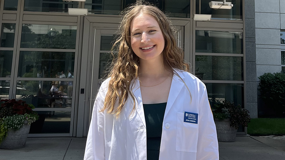 Jenna Somberg wearing her white coat outside in front of the Stritch building
